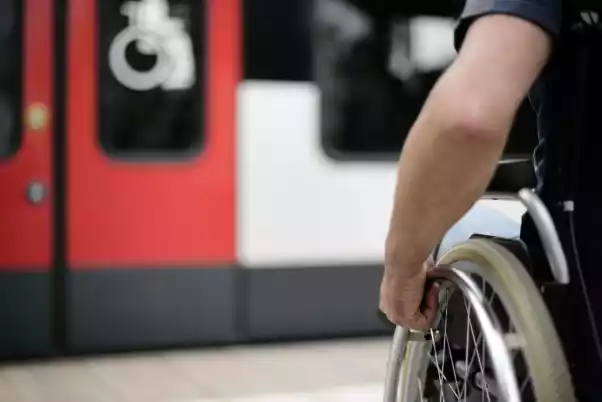 A wheelchair user at a station with barrier-free access waiting to board the train