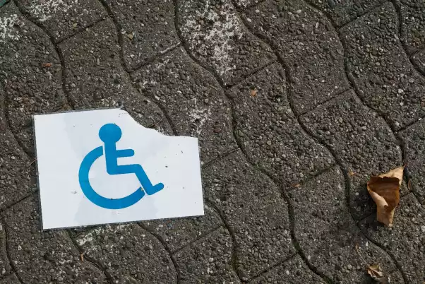 A torn and wet disabled person sign on the ground. (Photo: Shutterstock)