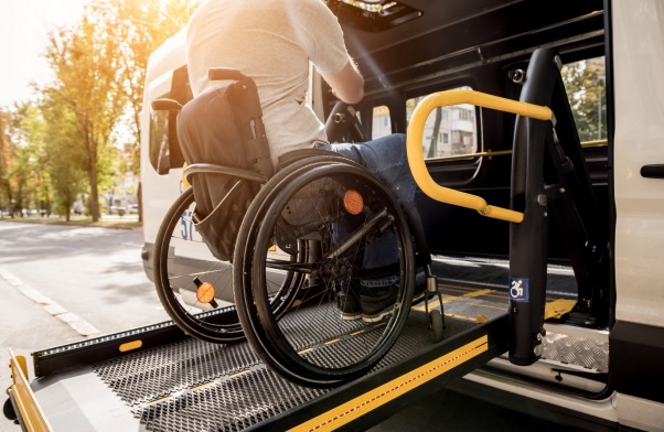 A man in a wheelchair on a lift of a vehicle for people with disabilities.